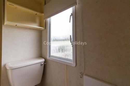 a bathroom with a toilet and a window at 8 Berth Caravan At California Cliffs Holiday Park In Norfolk Ref 50007d in Great Yarmouth