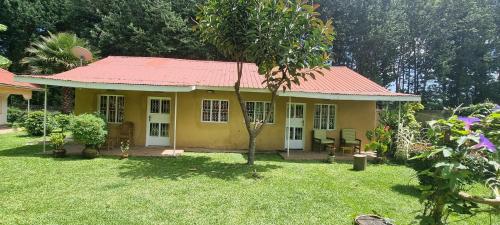a small yellow house with a red roof at Mutolere Coffee Pot Guest Houses in Kisoro