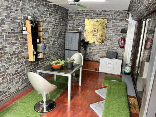 Lovely Cozy Apartment in the entrance of Nicosia في Aglantzia: غرفة مع طاولة وكراسي وجدار من الطوب