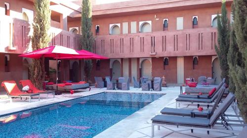 a pool with chairs and umbrellas next to a building at Kenzi Club Agdal Medina - All Inclusive in Marrakesh