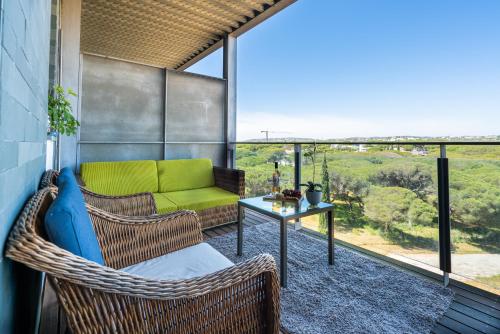 a balcony with wicker chairs and a table with a green couch at 1 Bed With Balcony Pool and Tennis in Quarteira