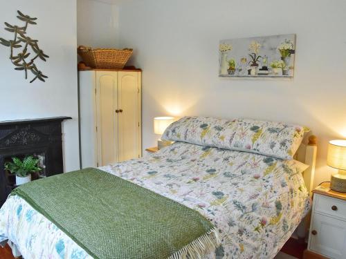 a bedroom with a bed with a green comforter at Fern Cottage in Bardon Mill