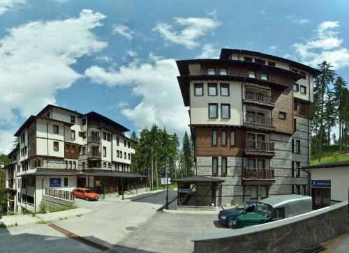 a tall building with a car parked in front of it at Green Life Family Apartments Pamporovo in Pamporovo