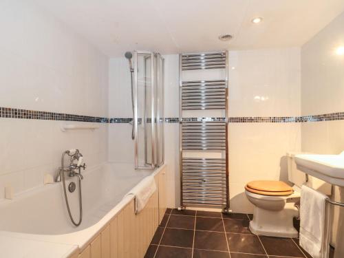 a bathroom with a toilet and a tub and a sink at Oak Barn in Cullompton