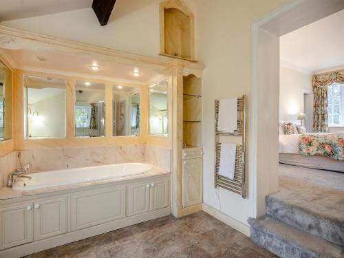 a large bathroom with a tub and a bedroom at White House Farm in Sedgeford