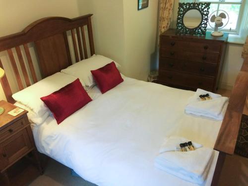 Schlafzimmer mit einem weißen Bett und roten Kissen in der Unterkunft Orchard Cottage At Braidwood Castle - Uk10671 in Braidwood