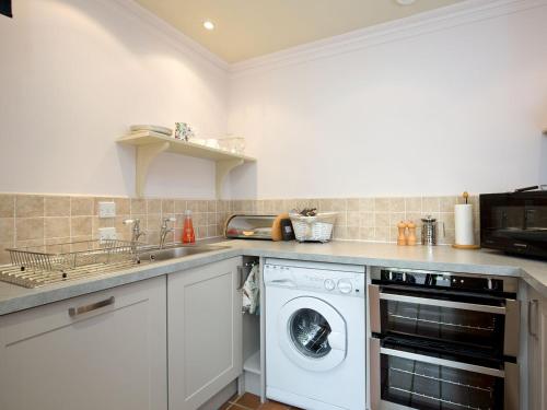 eine Küche mit einer Waschmaschine und einem Waschbecken in der Unterkunft Orchard Cottage At Braidwood Castle - Uk10671 in Braidwood