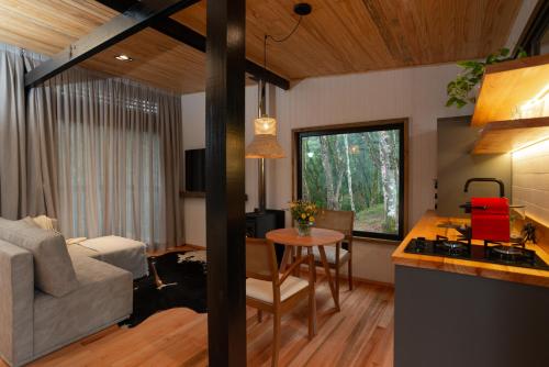 eine Küche und ein Wohnzimmer mit einem Sofa und einem Tisch in der Unterkunft Green Barn Hotel & Bistro in Urubici