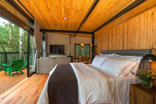 a bedroom with a large bed and a balcony at Green Barn Hotel & Bistro in Urubici
