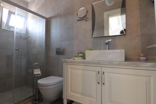 a bathroom with a toilet and a sink and a mirror at Alacaat Otel in Alaçatı