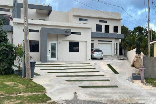 a white house with a car parked in front of it at Luxury 1 Bedroom & Rooftop Pool unit #2 in Falmouth