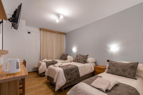 a hotel room with two beds and a tv at Hotel Sol del Sur in Esquel