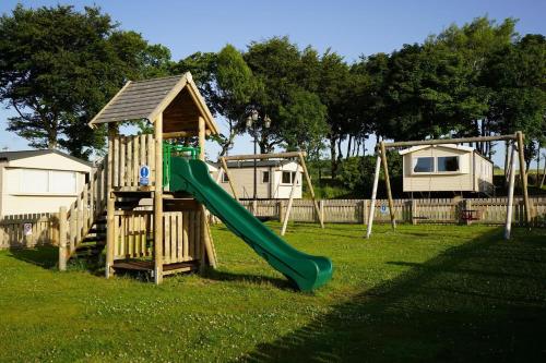 a playground with a slide and a play structure at Wrights Retreat 4 Lunan View St Cyrus Caravan Park in Saint Cyrus