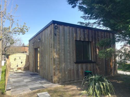 un hangar en bois avec une fenêtre dans la cour dans l'établissement Le Gîte insolite Gonnedouillé, à Gonneville-en-Auge