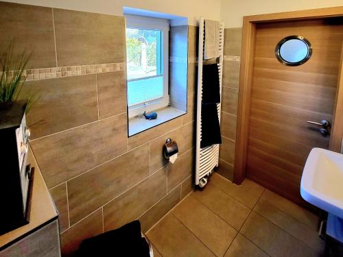 ein Bad mit einem Waschbecken und einem Fenster in der Unterkunft Ab unters Reet in Born