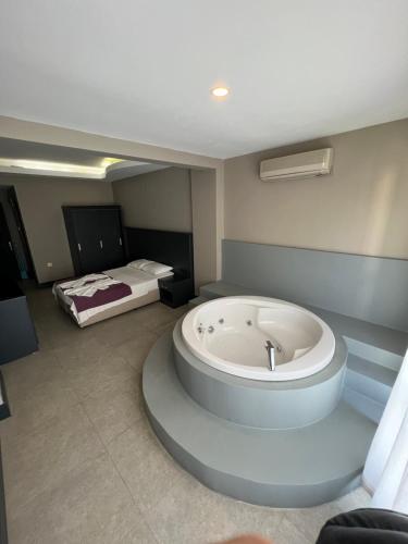 a room with a bath tub with a bed in the background at İzmah Apart Ölüdeniz in Fethiye