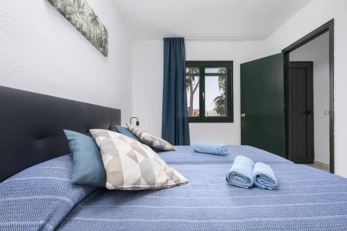 een slaapkamer met een blauw bed met blauwe kussens bij Blue Pearl in La Oliva