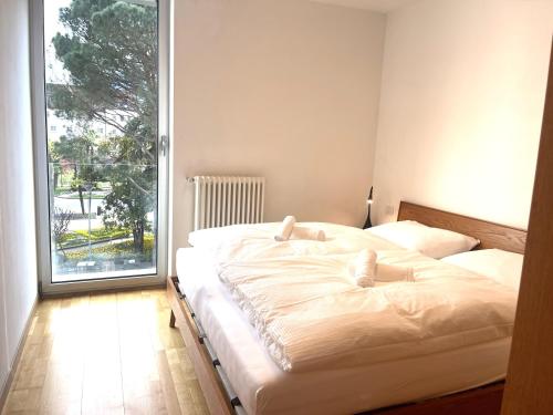 a bedroom with two beds and a large window at Kurhaus Apartment + parking in Merano