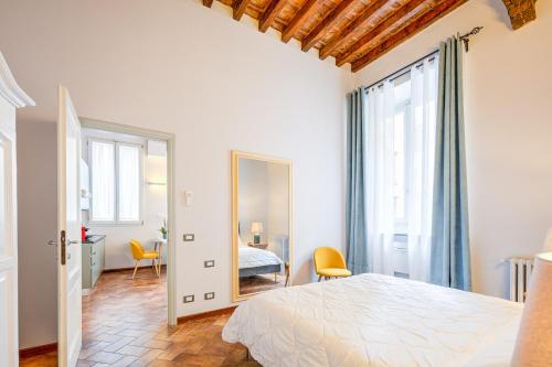Habitación blanca con cama y espejo en Condotta 16 Apartments, en Florencia