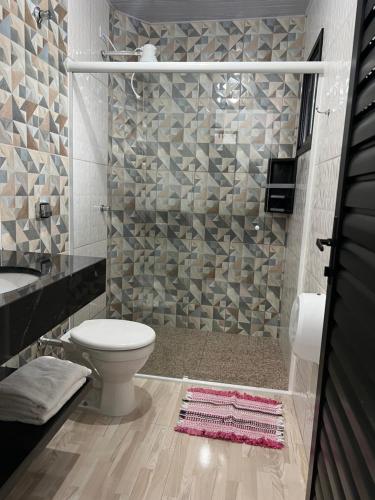 uma casa de banho com um chuveiro, um WC e um lavatório. em Pousada Maria Helena em Guaratuba