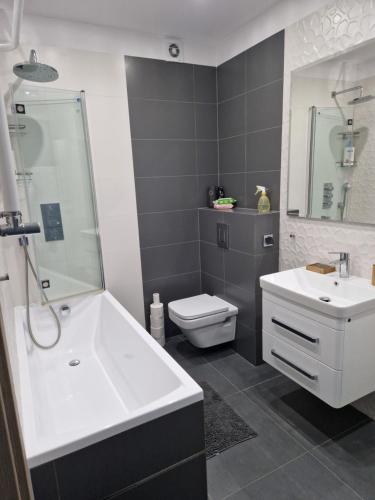 a bathroom with a tub and a sink and a toilet at Słoneczny Apartament in Suwałki