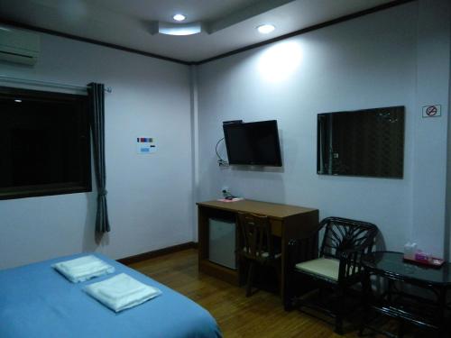 a room with a bed and a desk and a television at Garden Place in Phetchabun
