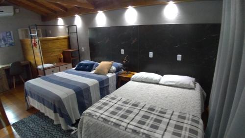 um quarto com 2 camas e uma parede preta em Moradas Desterro, próximo ao aeroporto 24 em Florianópolis