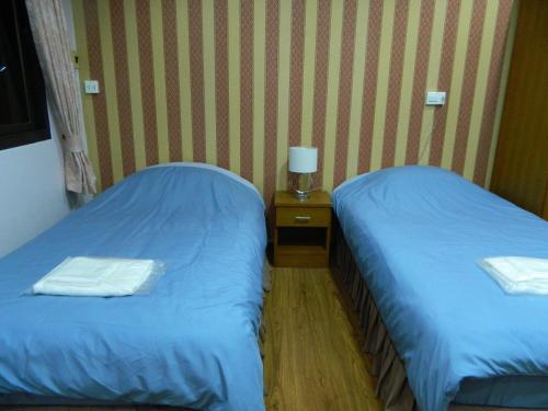 two twin beds in a room with a night stand at Garden Place in Phetchabun