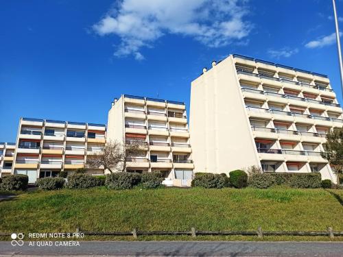 un grand bâtiment blanc avec une pelouse devant dans l'établissement Le Voilier - Appartement vue mer, à Saint-Jean-de-Monts