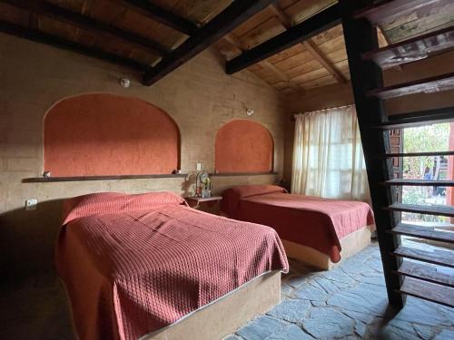 タスコ・デ・アラルコンにあるHotel SPA Campestre Los Adobesの赤いシーツが備わるドミトリールームのベッド2台