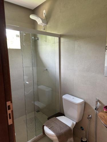 a bathroom with a toilet and a glass shower at Lençóis em cantos in Lençóis