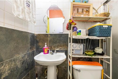 a bathroom with a sink and a toilet and shelves at Colorful Private Room Oasis in Montego Bay