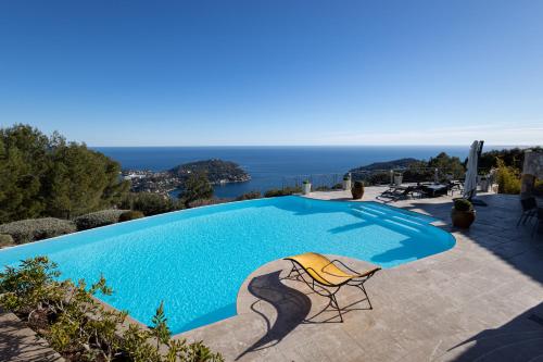a swimming pool with a chair and the ocean at Villa The View in Villefranche-sur-Mer