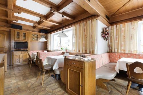 a dining room with tables and chairs and a kitchen at Pension Glockenstuhl in Finkenberg