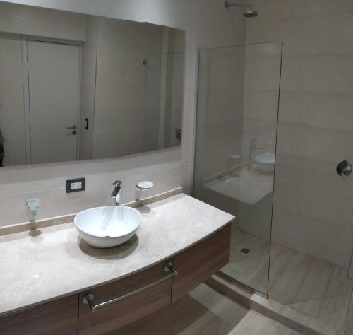 a bathroom with a sink and a glass shower at Altos de Mendoza II in Las Heras