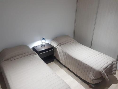 duas camas num quarto com um candeeiro sobre uma mesa em Altos de Mendoza II em Las Heras