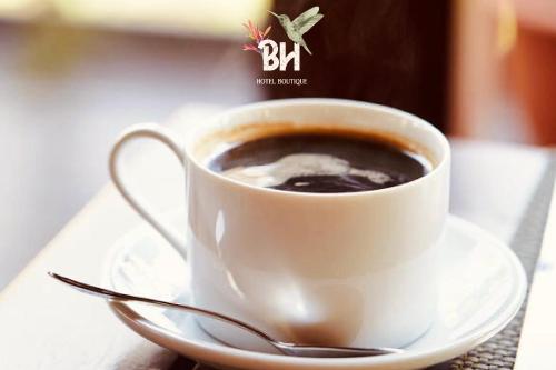 a cup of coffee on a saucer with a spoon at Bunde Haus Hotel EXPRESS BOUTIQUE in Ibagué