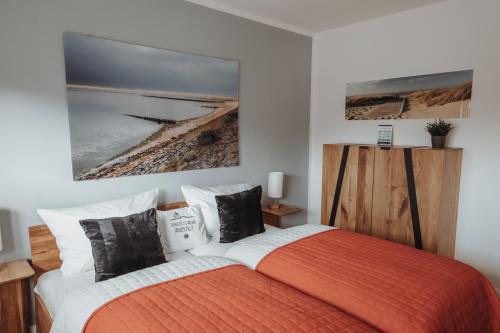 a bedroom with a bed with an orange and white blanket at Deine MEERZeit in Büsum