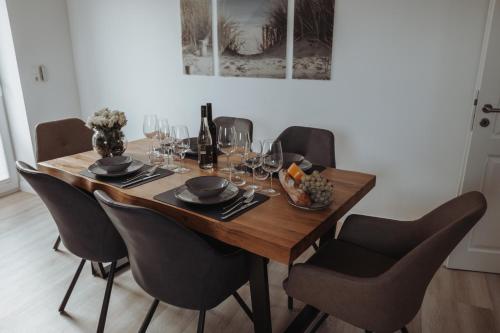 a dining room table with chairs and wine glasses at Deine MEERZeit in Büsum