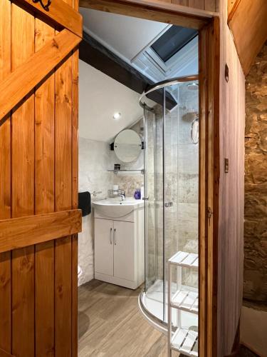 uma casa de banho com um chuveiro e um lavatório. em Old Nursery em Coity