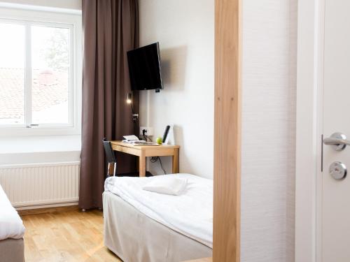 a bedroom with a bed and a desk with a computer at Hotell Svanen in Kalmar