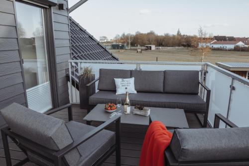 a balcony with a couch and chairs and a table at Deine MEERZeit in Büsum