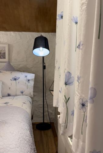 a bedroom with a bed and a lamp and curtains at Old Nursery in Coity