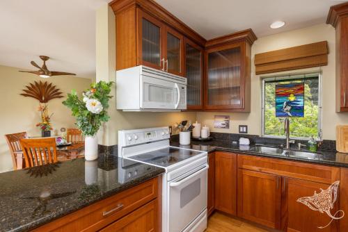 a kitchen with wooden cabinets and a white stove top oven at Hale Hahalua - Serenity and Ocean Views in Kailua-Kona at Keauhou Akahi above Keauhou Bay in Kailua-Kona