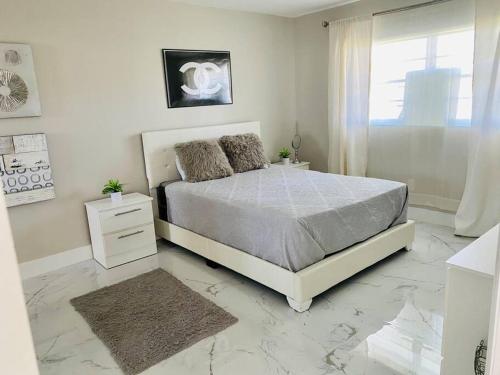 a white bedroom with a bed and a window at Stylish 1BR Condo 1Block to Aventura Mall in Aventura