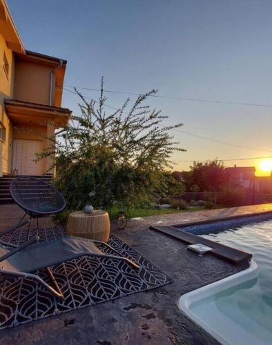 a pool with a table and a chair next to a house at Vila Sunset Jugovo in Udovice