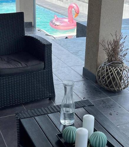 a glass vase on a table next to a chair and a pool at Vila Sunset Jugovo in Udovice
