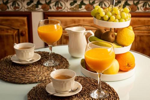 a table topped with glasses of orange juice and fruit at La Barbería de Miguel in El Chorro