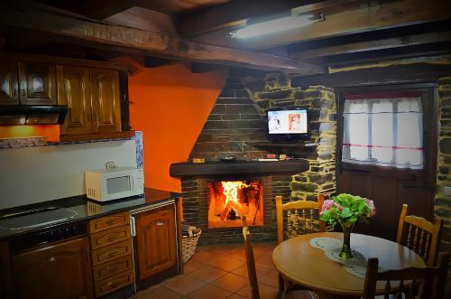 a kitchen with a fireplace and a table in front of it at Casa Freixe Apartamentos Rurales in Santa Eulalia de Oscos