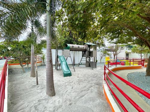 a playground with a slide in the sand and trees at Hannah’s Morning Sun - Studio Room in Manila